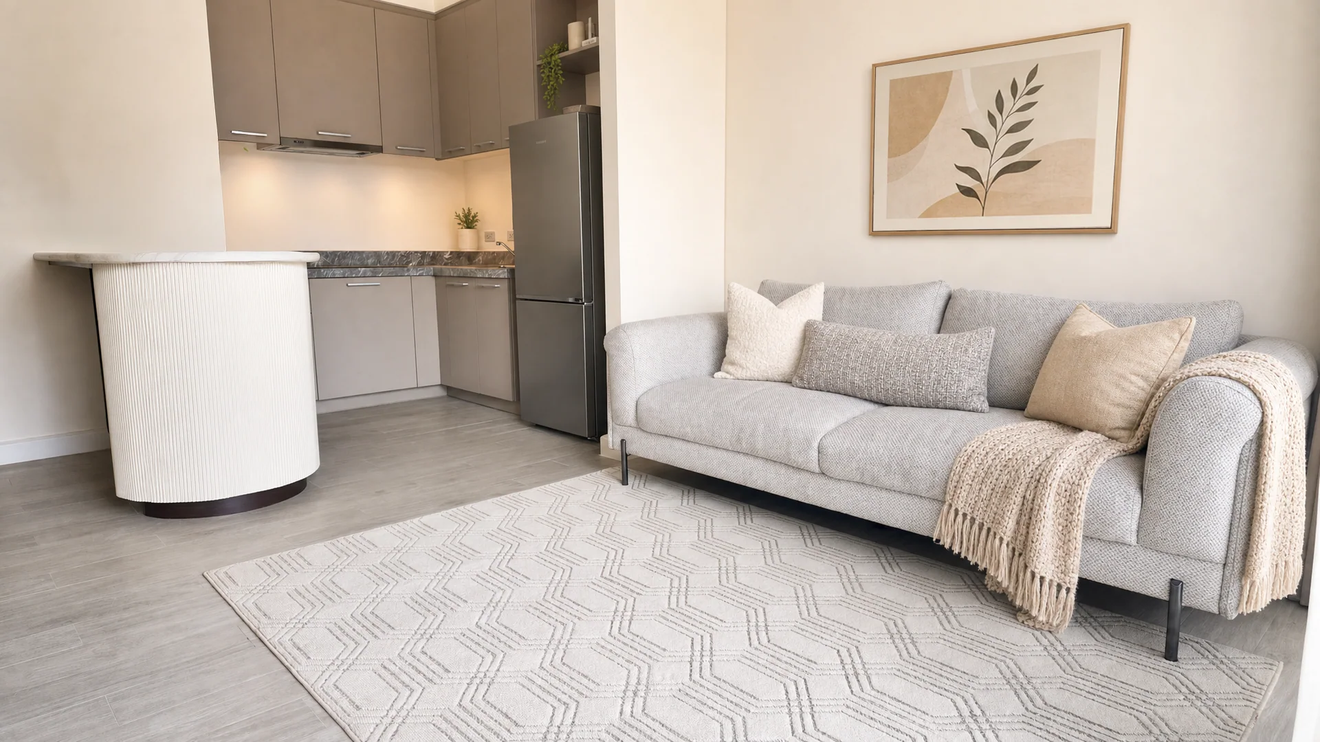 Rockwell living space with pale wood cabinetry, a light sofa, and an adjacent kitchen