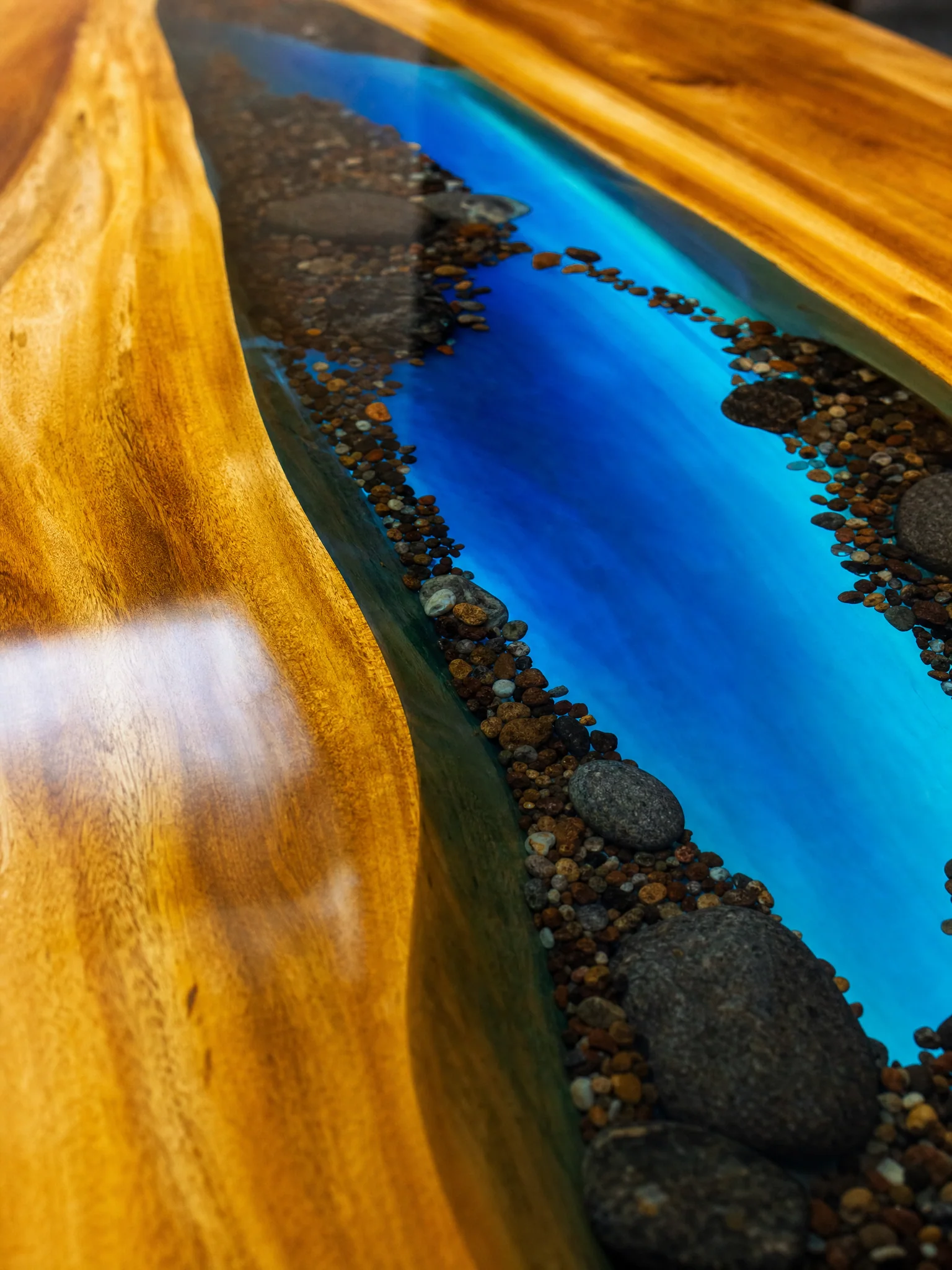 Natural river stones set within the blue resin river table